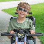 Child smiling and riding adaptive bike outside 