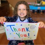 Child holding a colorful thank you sign
