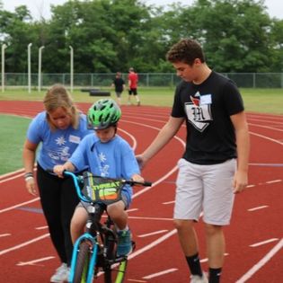 Volunteers assisting a boy learning to ride a bike