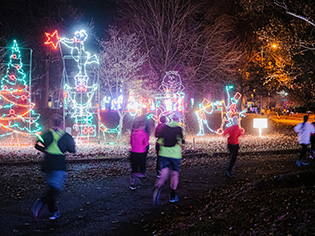 runners at night running past colorful light displays