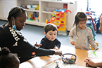 Woman at a table helping a boy and girl color