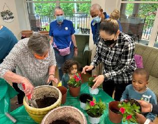 Adults and children planting flowers together at the Harry & Jeanette Weinberg Inter-Generational Center.