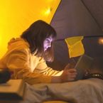 a girl uses a tablet inside a tent