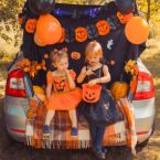 two children sitting in a car trunk decorated for halloween