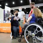 A women sitting in a wheelchair talking to a little person and two additional men standing behind her  
