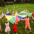 a group of children play with balls and a colorful parachute