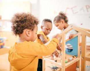 3 children in a classroom playing with toys.