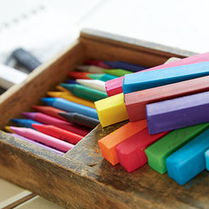 wooden box with colorful crayons inside and on top
