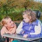 woman smiling at girl in wheelchair