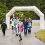 a group of people walk through a large white arch for the Final Lap walk of Move With Me
