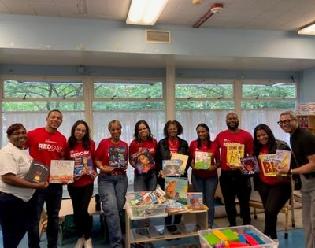 Menkiti Group employees holding up books with teachers at our Harry & Jeanette Weinberg Child Development Center.