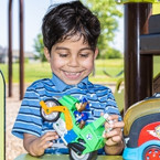 Boy smiling at park with a toy