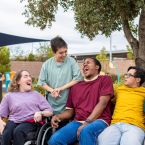 A photo of four individuals with disabilities interacting with each other. 
