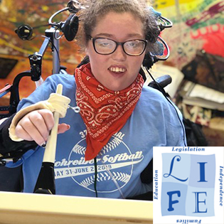 A disabled person in a wheelchair holding a paint brush