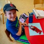 a young boy paints and smiles