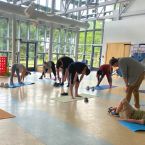 a group yoga class in a large room full of windows