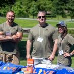 3 Veterans stand behind an ESMA Military & Veteran table